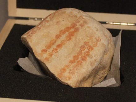 Fundstück aus dem Hohlen Fels bei Schelklingen, bemalt mit dunkelroten Punkten in zwei Doppelreihen.