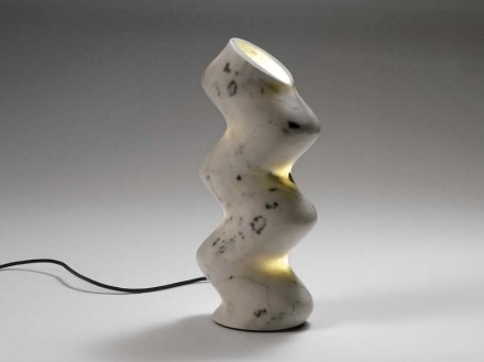 „Sinusoide“: <a href="http://www.marmiserafini.it"target="_blank">Marmi Serafini</a>. „Table lamp. Serafini treats marble like a radiant material, giving it innovative forms. NOME highlights the energy of this material, which is capable of creating unexpected plays of light. The lamp seems to change shape depending on the viewer’s perspective, while the alluring sinusoidal form conceals the complexity of its production.” Marmo Statuario.