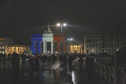 The Brandenburg Gate in Berlin in the colors of the French nation. At the right, flowers and candles in front of the French embassy.