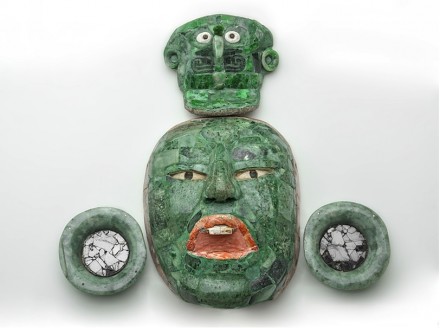 Begräbnismaske mit Ohrsteckern und Kopfschmuck. Jade, Obsidian und Muschel, 600–900 n. Chr., INAH, Campeche. Auf dieser Maske sind die drei Ebenen des Kosmos dargestellt: durch den Urzeitvogel auf der Kopfbedeckung, durch das Gesicht des begrabenen Würdenträgers und durch den Jaguargott der Unterwelt. Die Linie aus Spondylus calcifer, einer purpurfarbenen Muschel, umrahmt das Gesicht und verweist auf die unterirdische Wasserwelt.