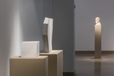 Blick in die Ausstellung. Im Hintergrund die älteste Arbeit, ein Kopf aus Kalkstein aus dem Jahr 1972, im Vordergrund die jüngste Arbeit, ein Marmorwürfel aus dem Jahr 2017.