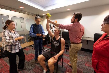 North Carolina State University basketball player Wyatt Walker models with a bunch of grapes at the team’s Dail Basketball Center practice facility in Raleigh while NCMA conservator Corey Riley, artist Larry Heyda, engineer Andrew Terrell, and NCMA Curator of Ancient Art Caroline Rocheleau help place his arm to fit the Statue of Bacchus.