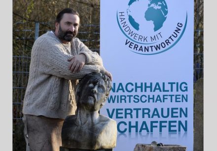 Timothy Vincent vor dem Plakat einer anderen seiner Initiativen, bei der es um die von großen Konzernen praktizierte Coporate Social Responsibility im Handwerk geht. Foto: Timothy Vincent