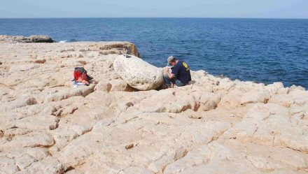 Einer der Wissenschaftler untersucht einen Findling, der vom Tsunami auf die Klippen geschleudert worden war. Foto: Gösta Hoffmann/Uni Bonn