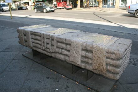 Granitbank von Ugur Ötzbay an der Bushaltestelle vor Woolworth („Wulle“), Potsdamer Straße am Rand des Frobenkiezes. Geplant war ehemals ein ganzer Boulevard der Bänke.