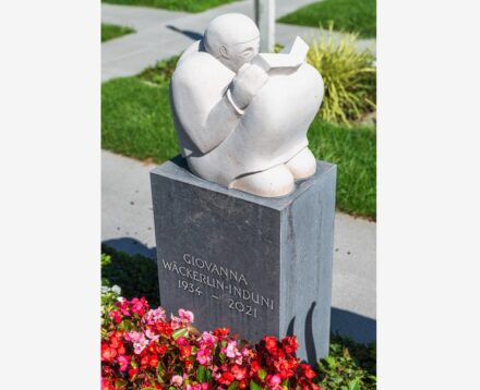 The crouching woman made of Comblanchien limestone with a scraped surface appears to be deeply immersed in a book. Everything about her is round and at rest. In contrast to this is the pedestal on which the figure rests. Its material is Belgian granite with a polished surface and precise corners. Sculptor: Christopher Gut, Riehen.