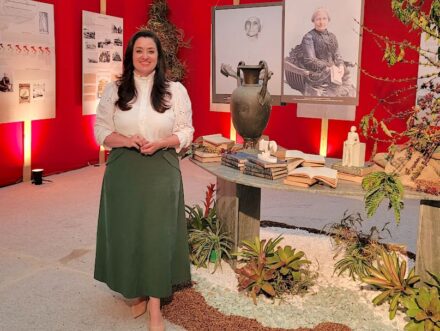 Araciene Scaramuzza Pessin, Brazilian natural stone entrepreneur and designer, in her exhibition. The pictures on the wall behind her show the second generation of immigrants, namely great-grandmother Ágatha Marabotti.