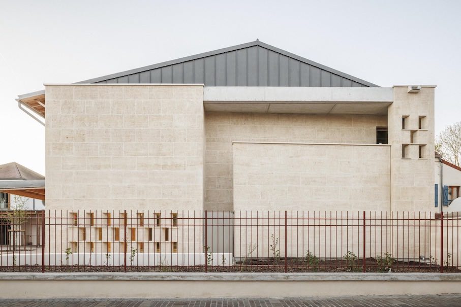 A solid natural stone wall separates the extension of the École Maternelle in the town of Montfermeil from the street